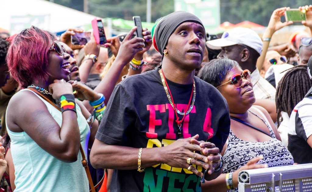 Grande massa de público que curte o estilo reggae participando de um show em uma praça pública.