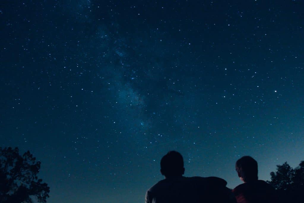 Silhueta de duas pessoas admirando as estrelas.