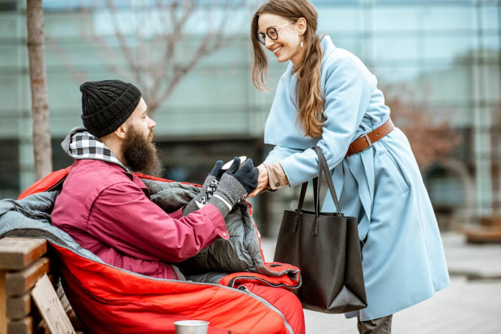 Mulher sorrindo entregando um copo para homem que está sentado em um banco de madeira