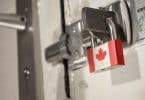 Porta trancada com fechadura de ferro, presa com um cadeado com a bandeira do Canadá.