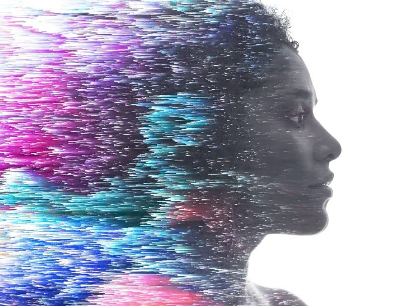 Ilustração de mulher de perfil, com a parte de trás dele se decompondo em pequenos pontos de luz coloridos.