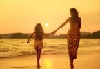 Mãe e filha caminhando na praia