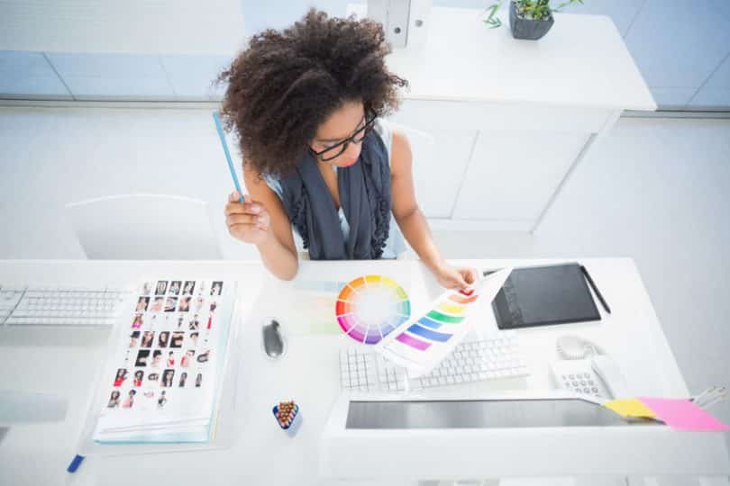 Mulher em mesa de trabalho analisando paleta de cores