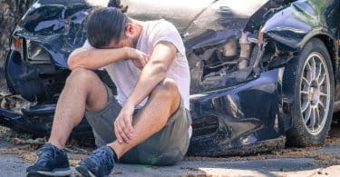 Homem triste chorando após acidente de carro.