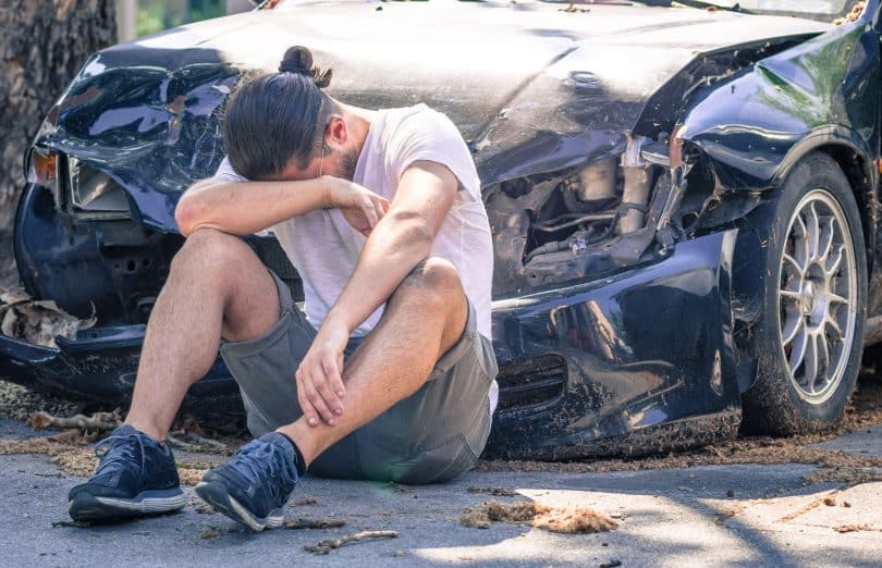 Homem triste chorando após acidente de carro.