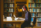 Homem sentado em uma biblioteca, estudando.