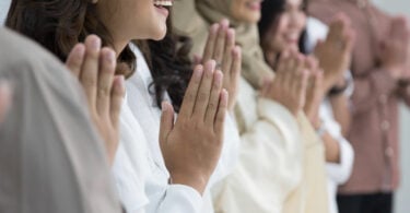 Grupo de pessoas de diferentes religiões lao a lado, rezando