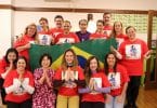 Grupo de pessoas com camisetas vermelhas, segurando uma bandeira do Brasil.