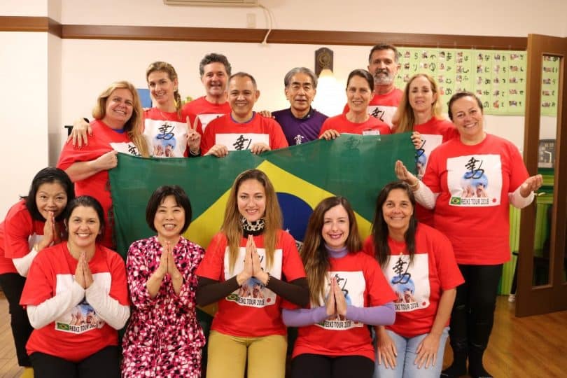 Grupo de pessoas com camisetas vermelhas, segurando uma bandeira do Brasil.