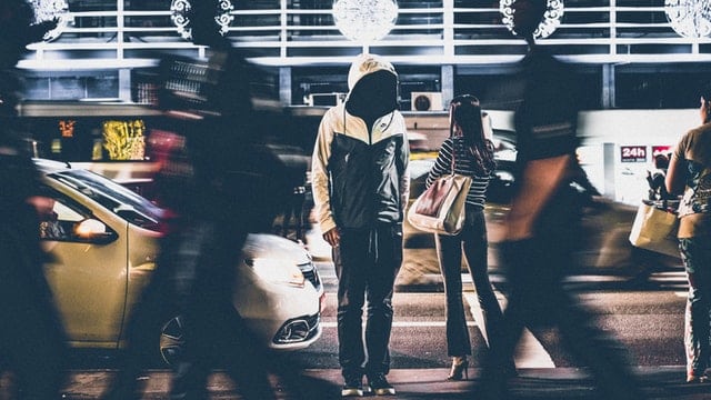 Pessoa parada na rua com outras pessoas em movimento ao lado