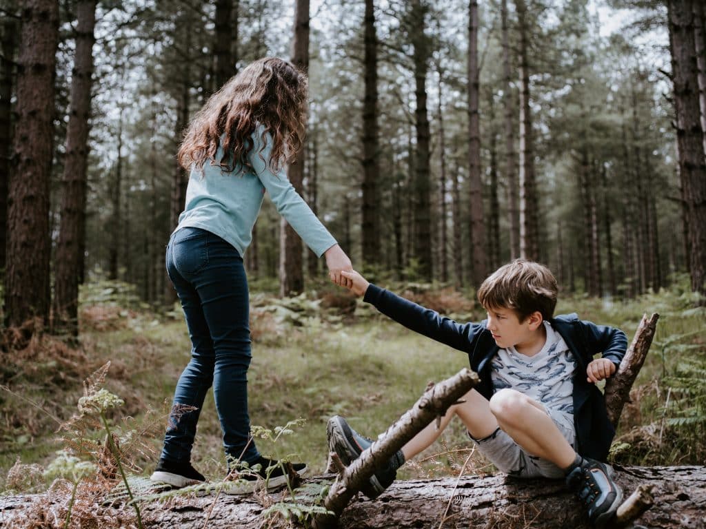 Menina ajudando menino a se levantar do chão