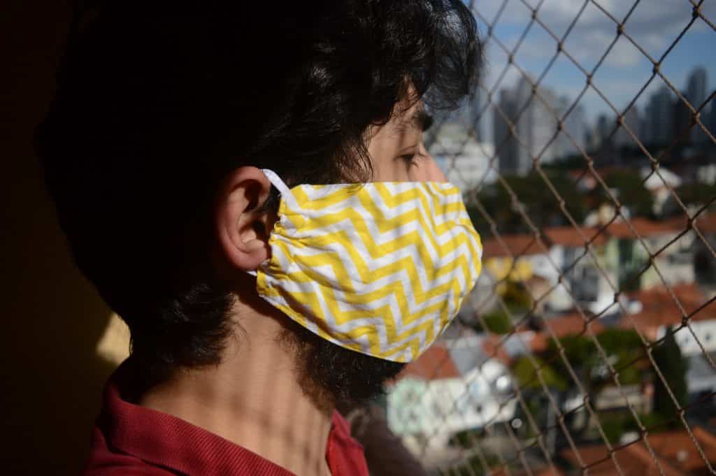 Homem usando mascara de proteção ao lado de uma grade