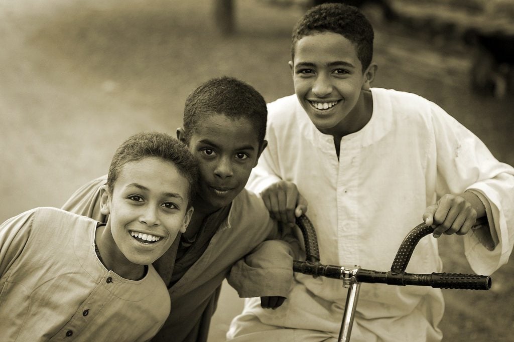 Imagem em preto e branco de três crianças amigas. O maior está sentado em uma bicicleta. Luto imagem.