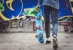 Adolescente segurando um skate enquanto anda