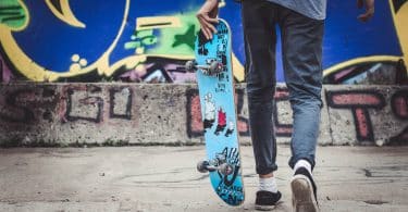 Adolescente segurando um skate enquanto anda