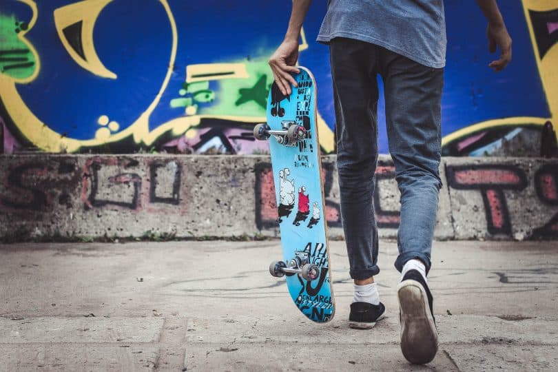 Adolescente segurando um skate enquanto anda
