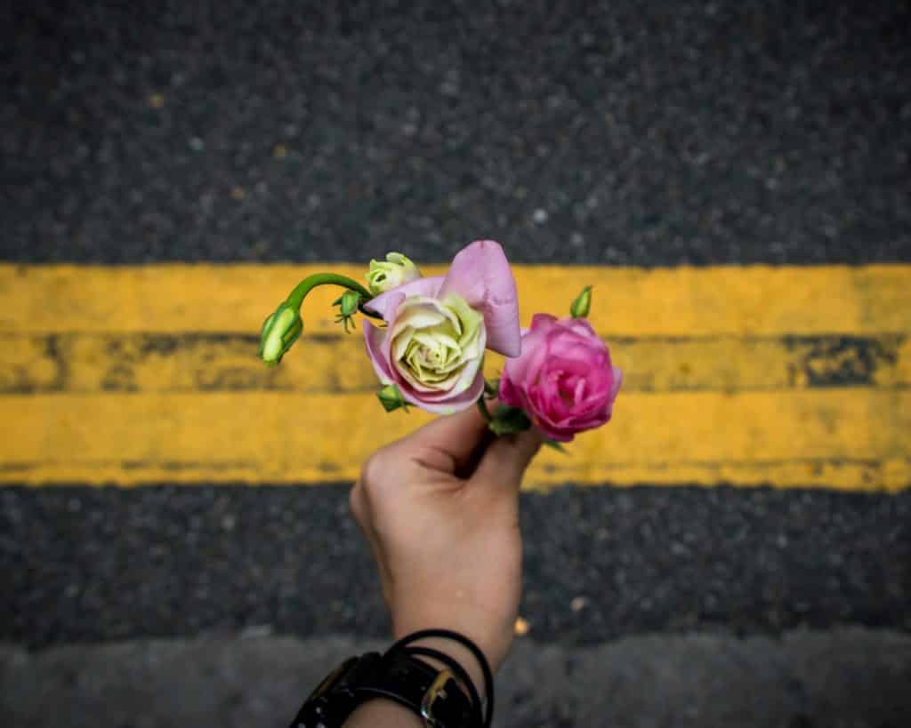 Pessoa segurando flores na direção da rua