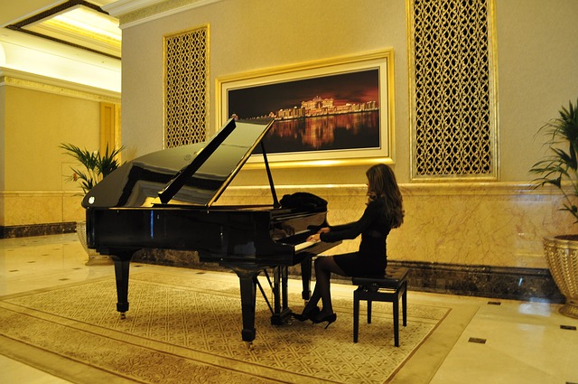 Mulher vestida toda de preto, tocando um piano de cauda.