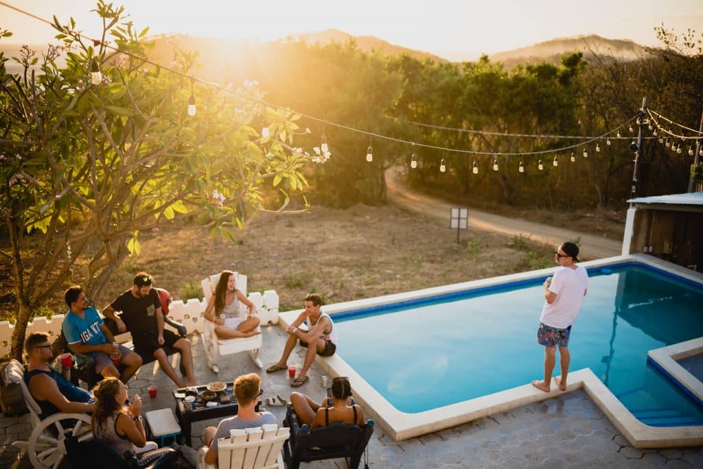 Amigos reunidos sentados em círculo ao lado de uma piscina.