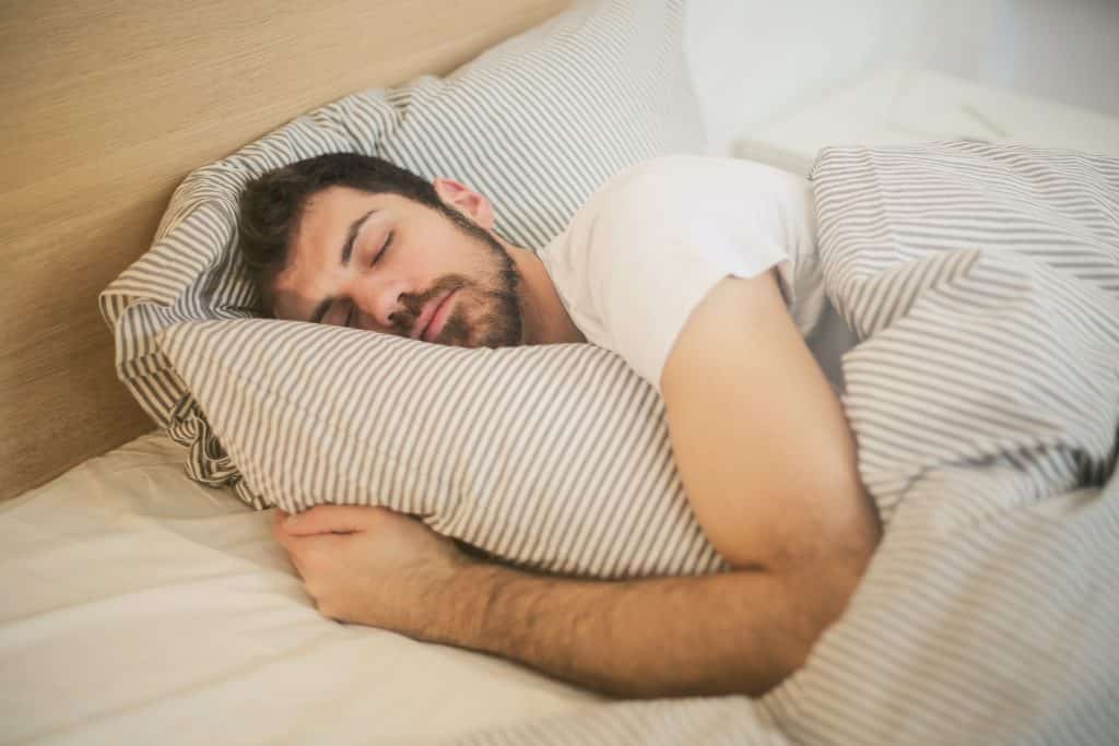 Homem deitado da cama, dormindo.