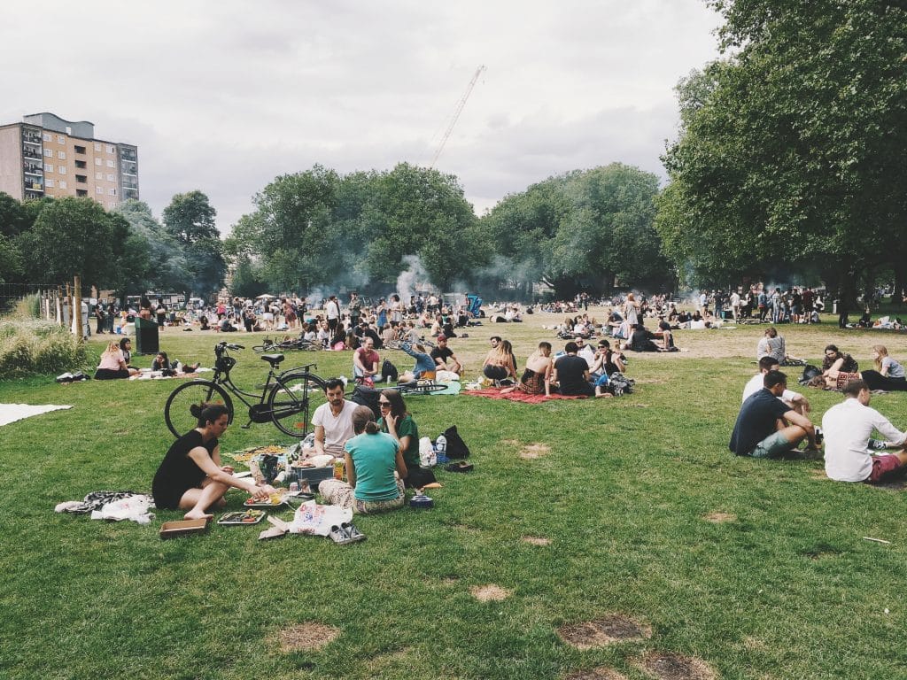 Grupo de pessoasl em um parque sentados conversando, sindo