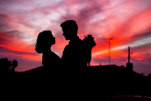 Silhueta de casal com céu rosa ao fundo