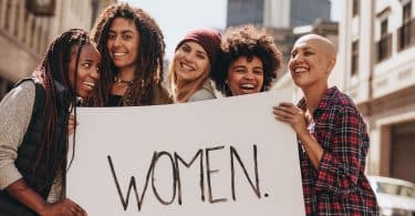 Mulheres na rua segurando cartaz escrito em inglês "women"