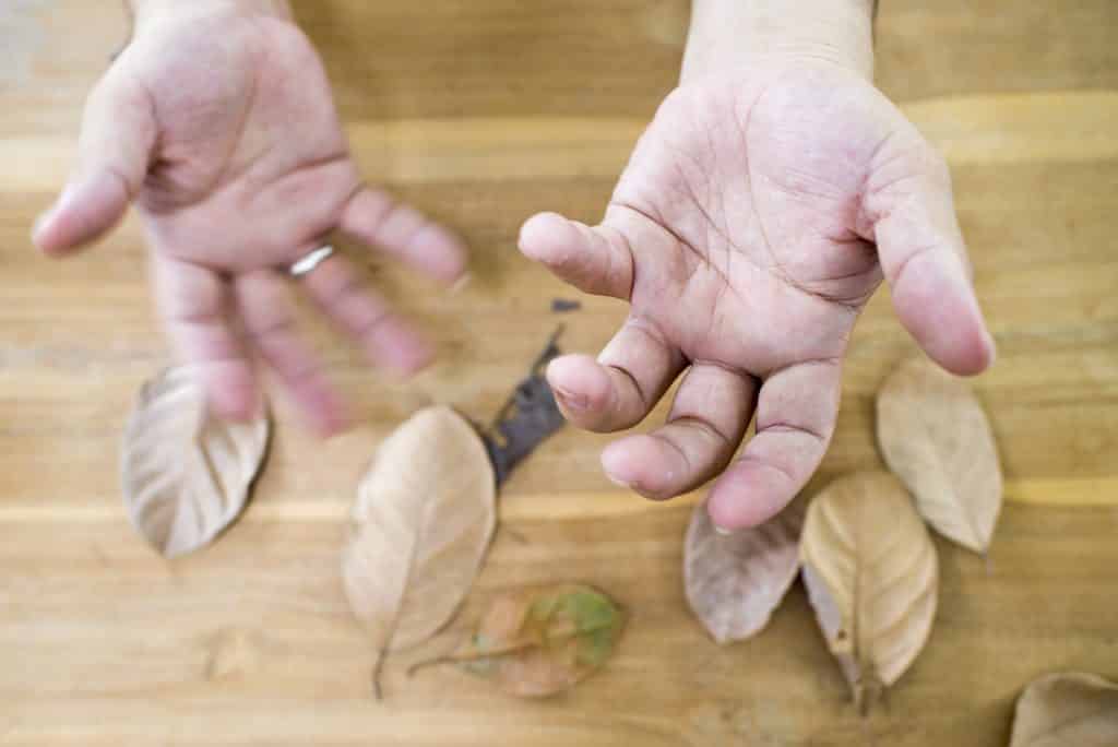 Imagem de mãos trêmulas de um senhor diagnosticado com parkinson.