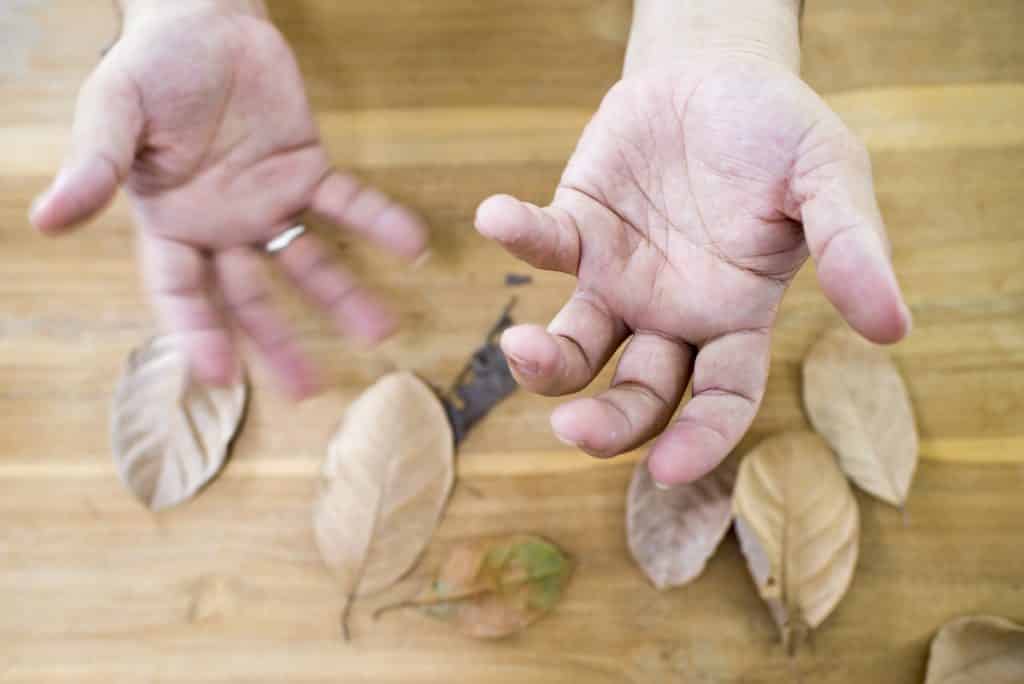 Imagem de mãos trêmulas de um senhor diagnosticado com parkinson.
