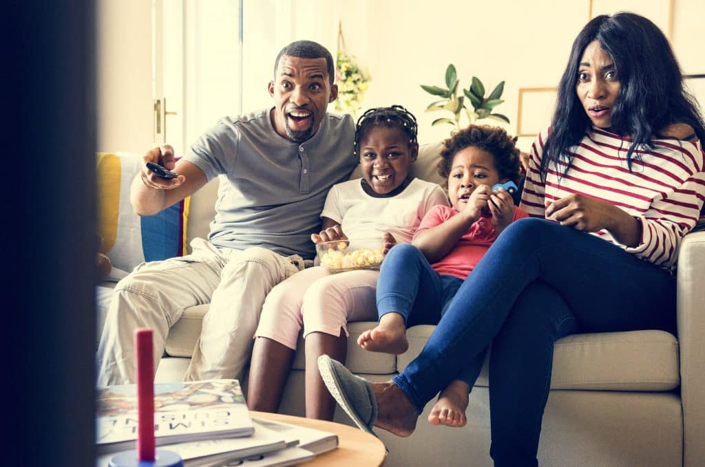 Família reunida no sofá da sala assistindo filme