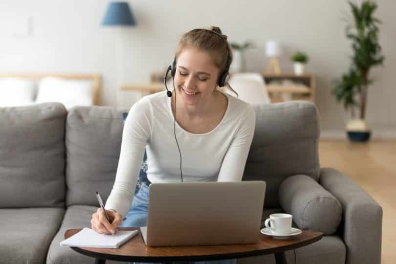 Mulher olhando para o computador sorrindo sentada no sofá