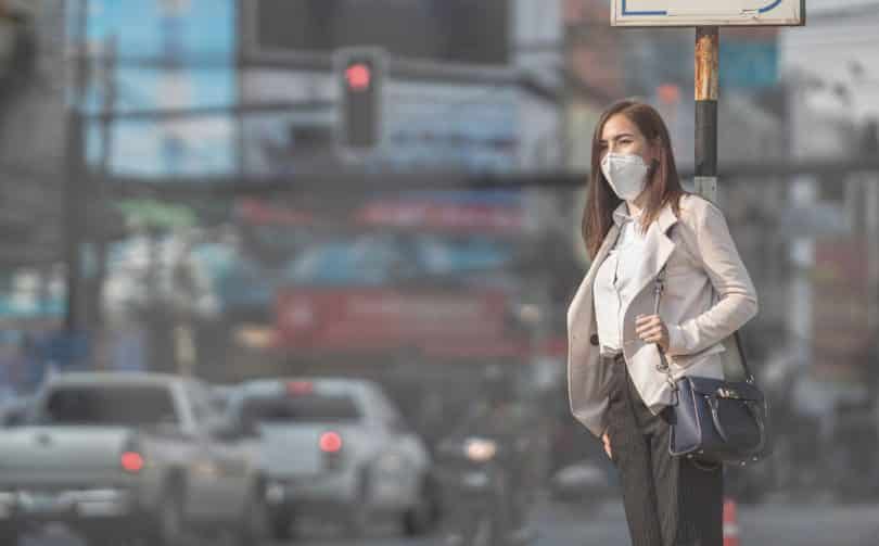 Mulher andando na rua com máscara de proteção no rosto
