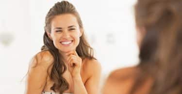 Mulher sorrindo enquanto olha seu reflexo no espelho
