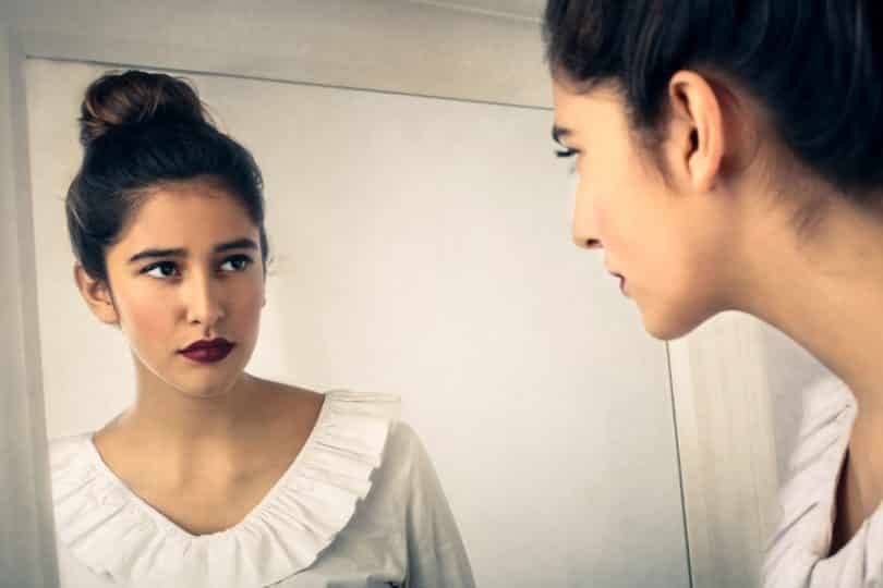 Mulher olhando seu reflexo no espelho com expressão séria