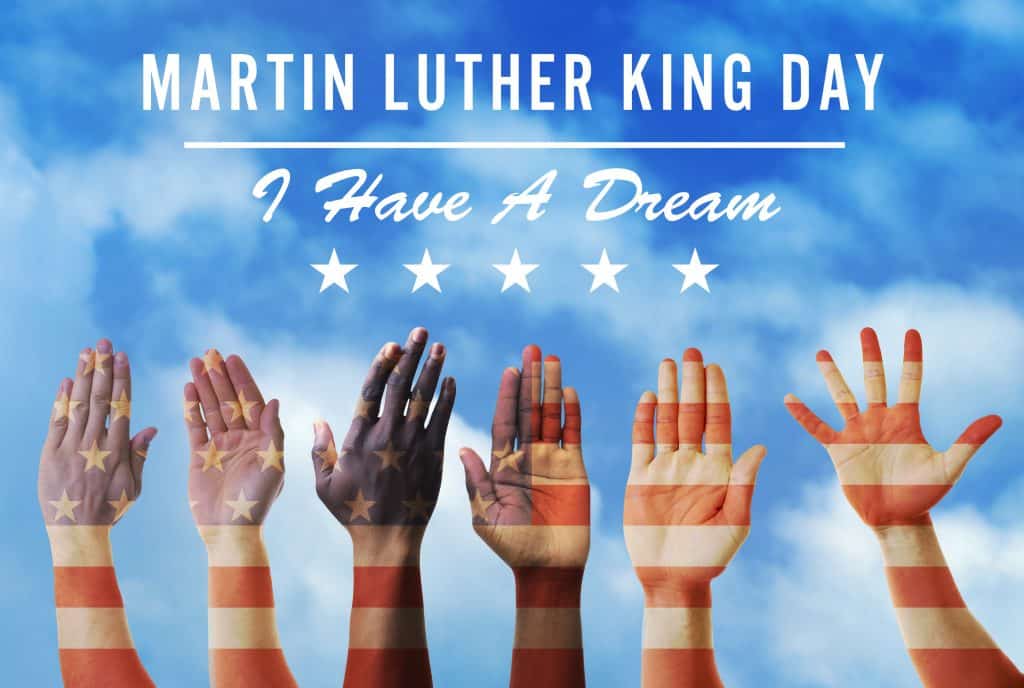 Imagem de várias braços erguidos. Eles estão pintados com as cores e os símbolos da bandeira dos Estados Unidos. Ao fundo a imagem do céu azul. Sobre ele a frase escrita: Dia de  Martin Luther King - Eu tenho um sonho.