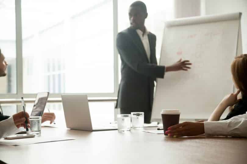 Homem apresentando seu projeto a uma mesa de trabalho.