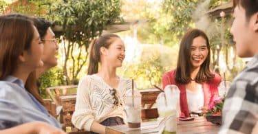 Grupo de pessoas sentadas ao redor de uma mesa com copos de suco vazios. Todos estão rindo.