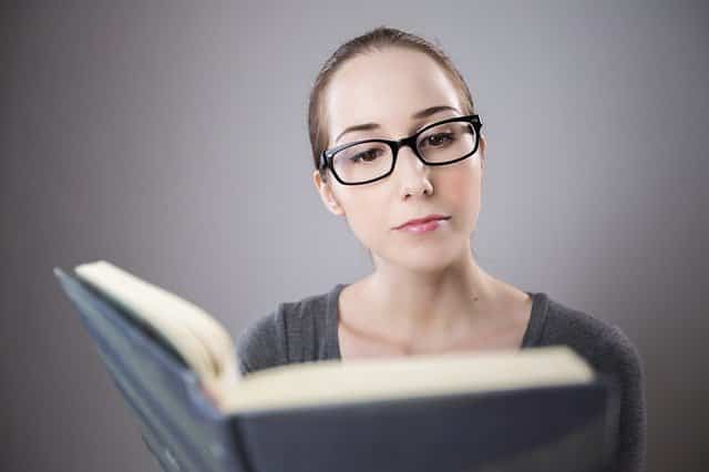 Mulher com óculos lendo livro