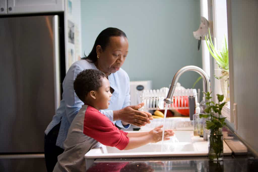 Mãe e filho lavando suas mãos na cozinha