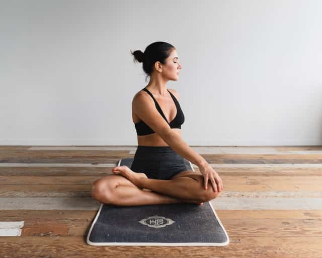 Mulher meditando em tapete em sala