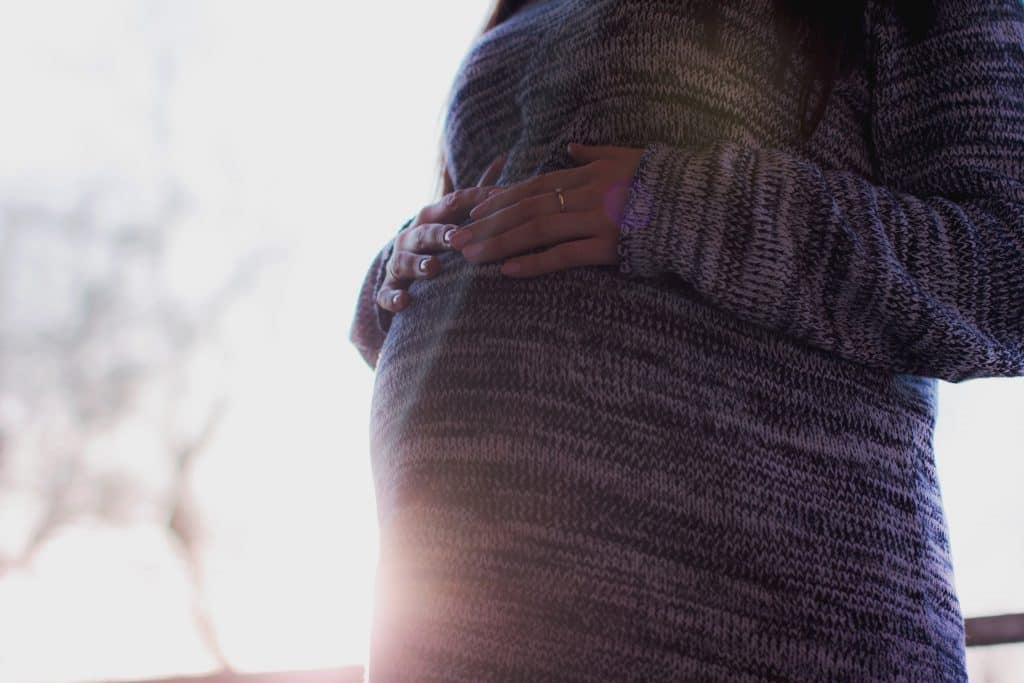 Mulher grávida com as mãos na barriga 