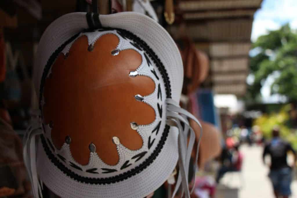 Imagem do tradicional chapéu nordestino pendurado em uma barraca no centro de uma cidade do nordeste.