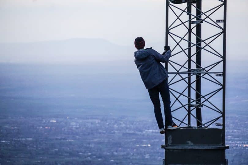 Pessoa se segurando em uma torre olhando para o mar um