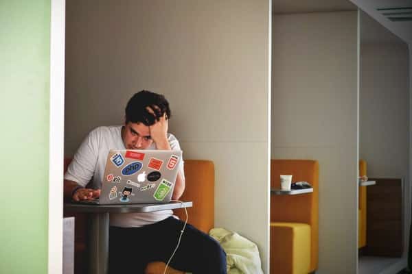 Homem mexendo no computador com mão na cabeça preocupado