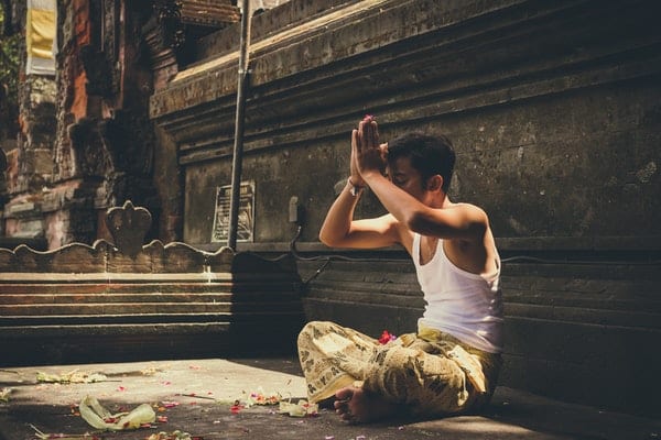 Homem meditando em templo de olhos fechados