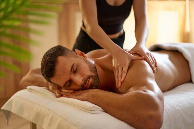 Homem deitado de bruços, recebendo massagem nas costas.