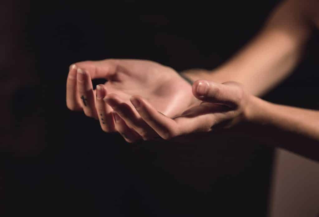 Mãos de uma pessoa estendidas com as palmas para cima, em sinal de oração.