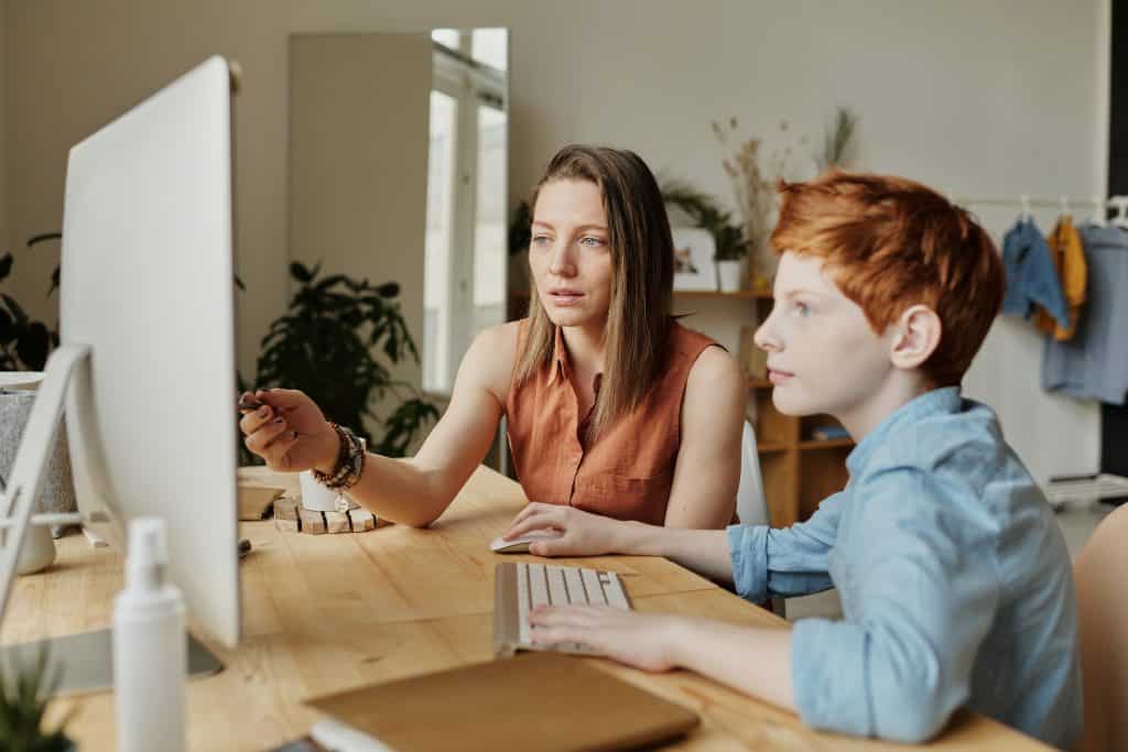 Mulher ajudando seu filho a usar o computador durante a quarentena.