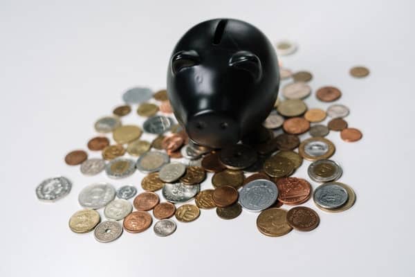 Porquinho de porcelana preto com moedas espalhadas embaixo dele
