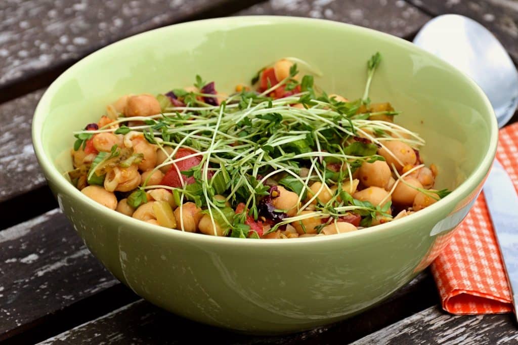 Imagem de uma bowl de porcelana na cor verde clara cheia de salada de grão de bico.